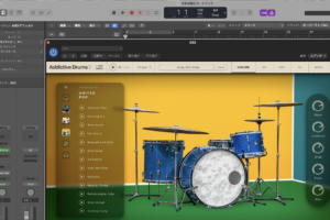 Addictive Drums 2 の EXPLORE 画面。プリセットキットのプレビューと、右側に Room・Overhead・Hihat・Snare・Kick のクイックミックスノブが並ぶ
