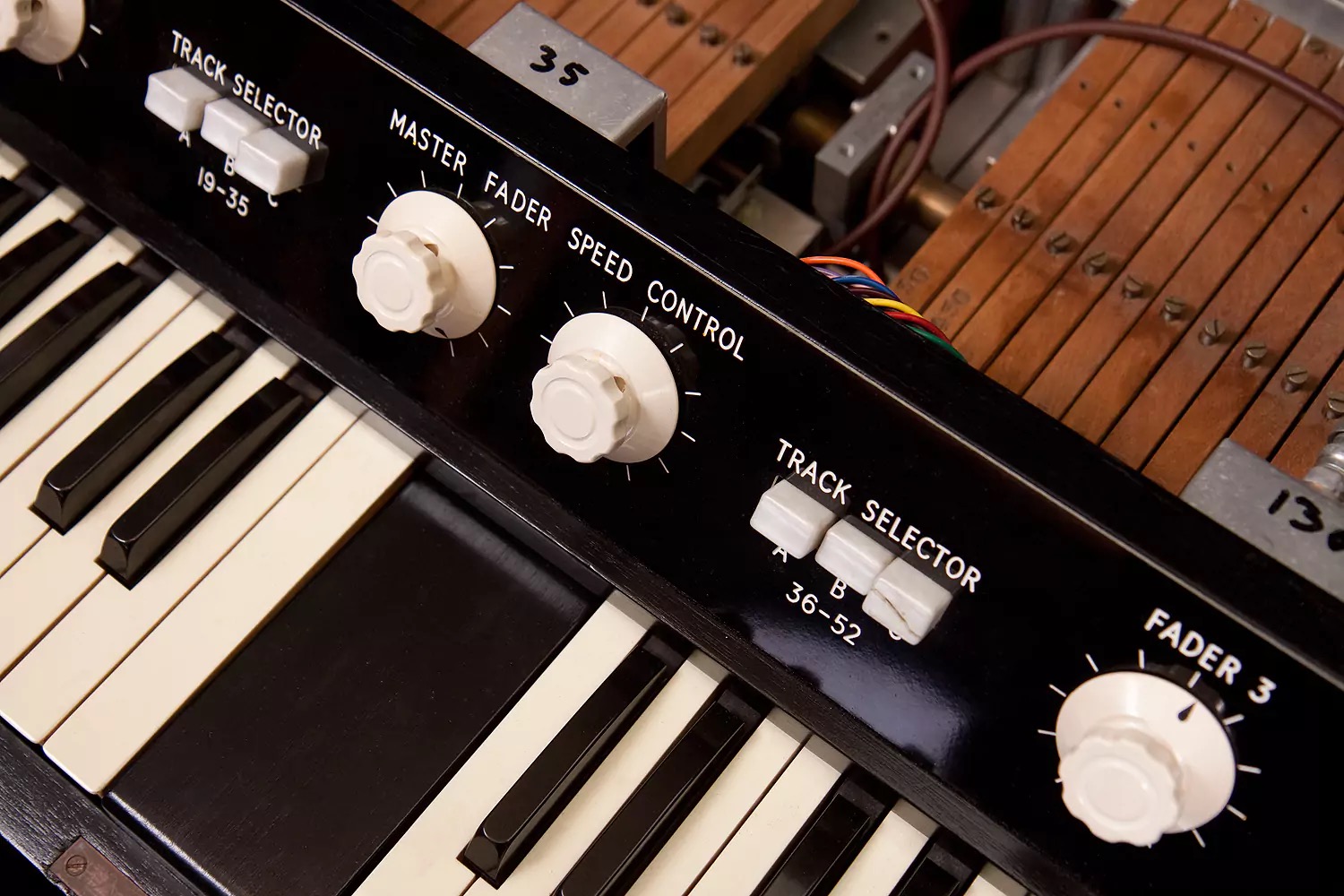実機のメロトロンの操作パネル。TRACK SELECTORのボタンとMASTER FADER・SPEED CONTROLのつまみ、奥に中の機構（GForce公式の M-Tron Mk II のページの写真）